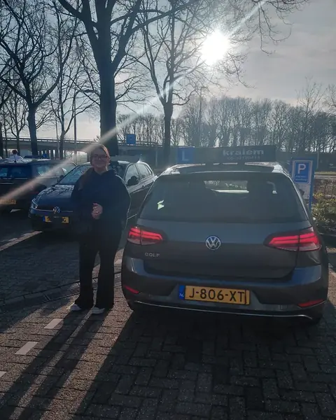 Geslaagde leerling bij de lesauto van Rijschool Kraiem bij het CBR-examencentrum