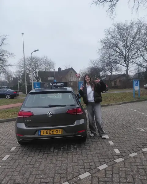 Leerling geslaagd voor haar rijbewijs naast de VW Golf lesauto van Rijschool Kraiem